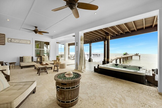 view of patio with an outdoor hot tub, an outdoor living space, ceiling fan, and a water view