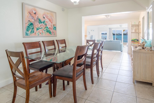 dining area with light tile patterned floors and a water view