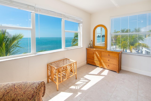 living area featuring plenty of natural light, light tile patterned flooring, and a water view