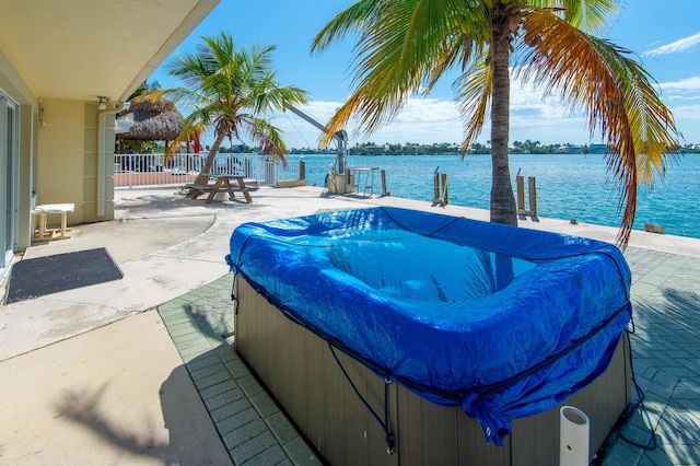 view of patio / terrace with a hot tub and a water view