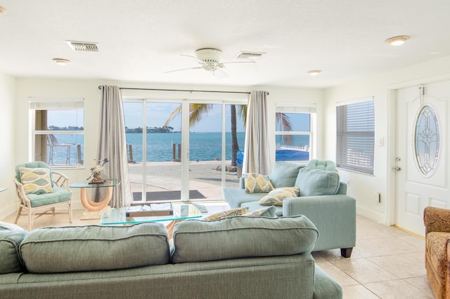 living room featuring light tile patterned flooring, ceiling fan, and a water view