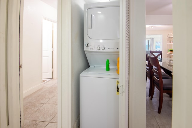 laundry area with light tile patterned flooring and stacked washer and clothes dryer