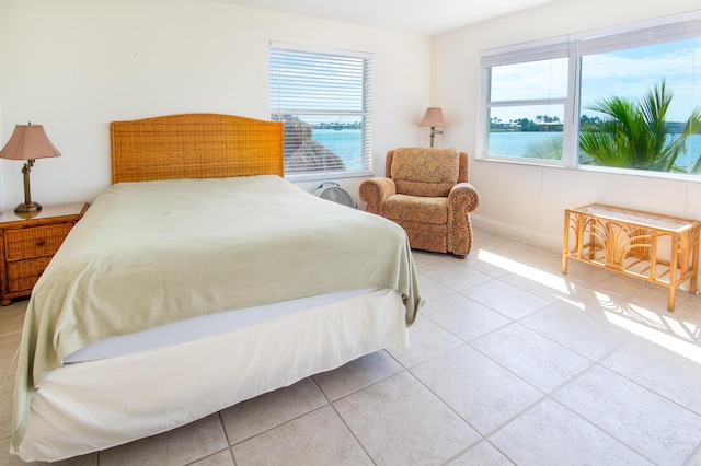 tiled bedroom featuring multiple windows and a water view