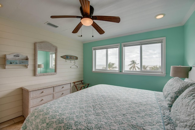 bedroom with ornamental molding, wooden walls, and ceiling fan