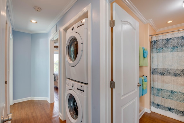 clothes washing area featuring hardwood / wood-style floors, crown molding, and stacked washer and clothes dryer