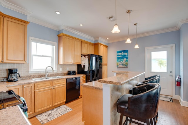 kitchen featuring a kitchen bar, sink, a kitchen island, pendant lighting, and black appliances