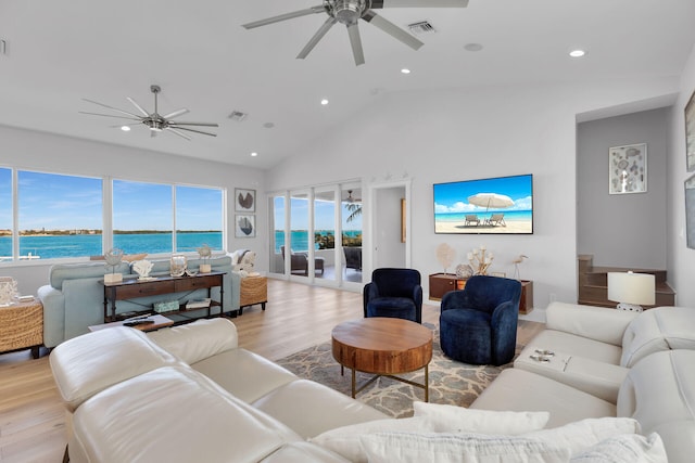 living room with plenty of natural light, light hardwood / wood-style flooring, ceiling fan, and a water view