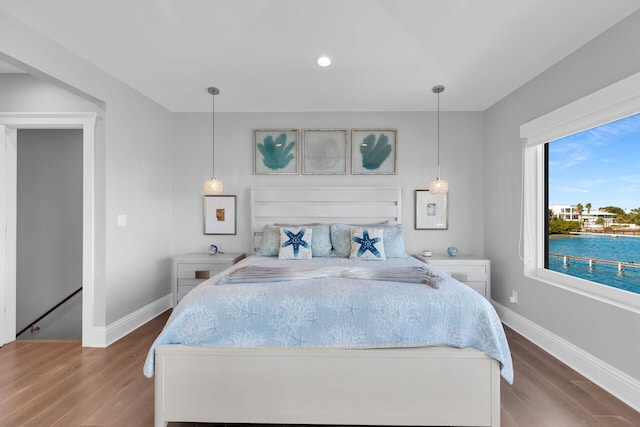 bedroom featuring hardwood / wood-style flooring and a water view