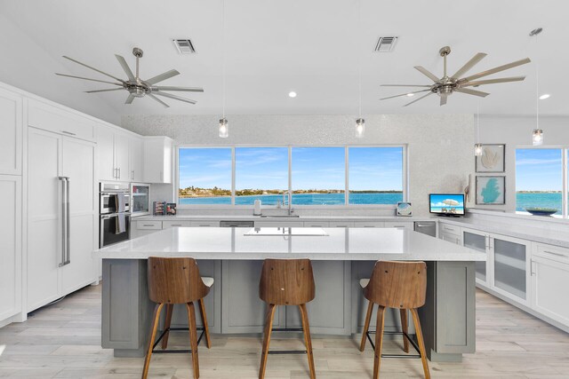 kitchen with a kitchen island, a breakfast bar, white cabinets, and ceiling fan