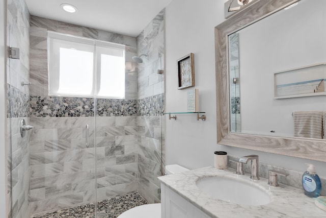 bathroom with vanity, a shower with shower door, and toilet