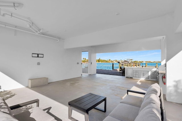 living room with a water view, sink, and concrete floors