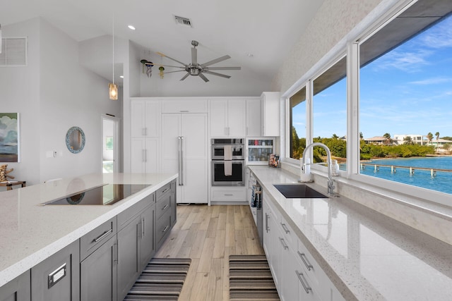 kitchen with a water view, sink, pendant lighting, and white cabinets