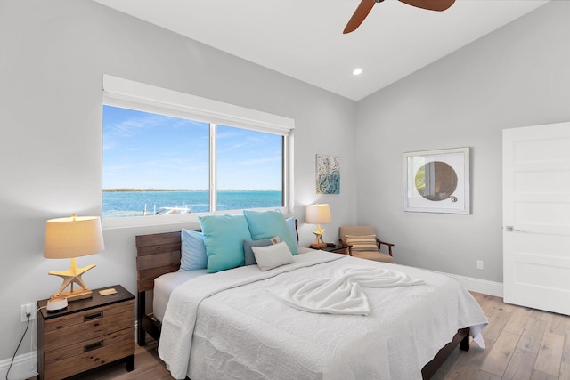 bedroom with vaulted ceiling, a water view, ceiling fan, and light hardwood / wood-style flooring