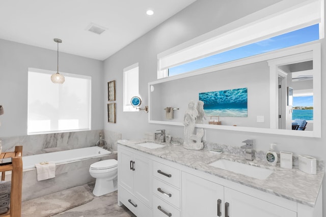 bathroom featuring vanity, tiled bath, and toilet