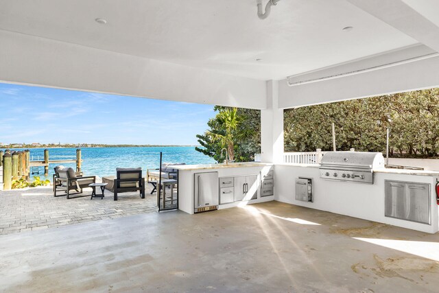 view of patio with area for grilling, sink, grilling area, and a water view