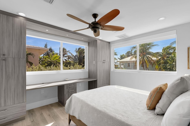 bedroom with light hardwood / wood-style flooring, built in desk, and ceiling fan