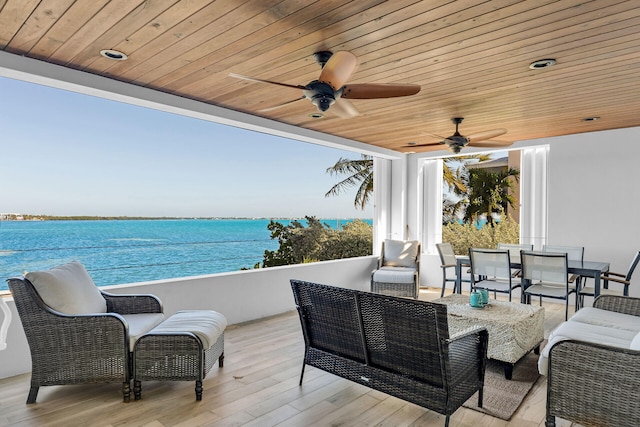 view of patio with a water view, ceiling fan, and an outdoor living space