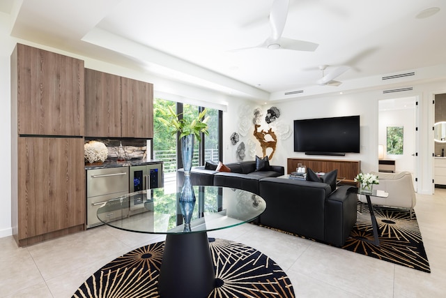 living room with light tile patterned floors, a raised ceiling, and ceiling fan