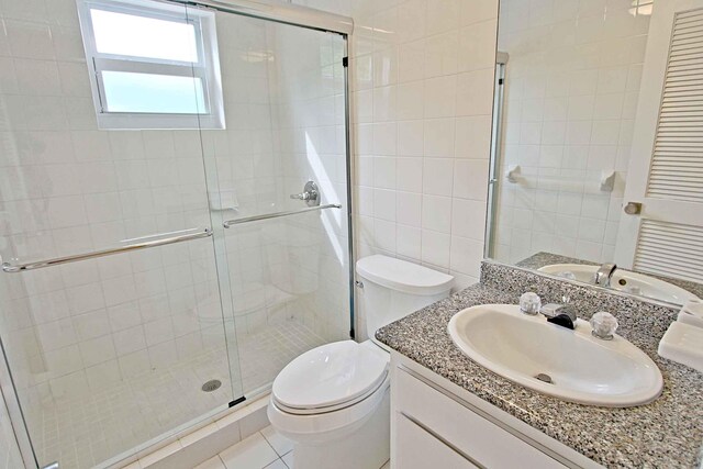 bathroom with walk in shower, vanity, tile patterned floors, and toilet