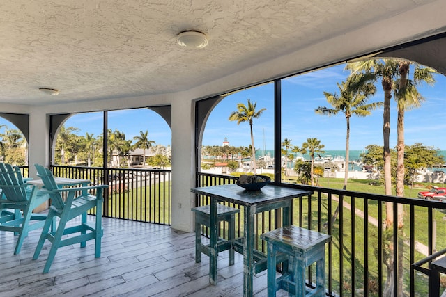 sunroom featuring a water view