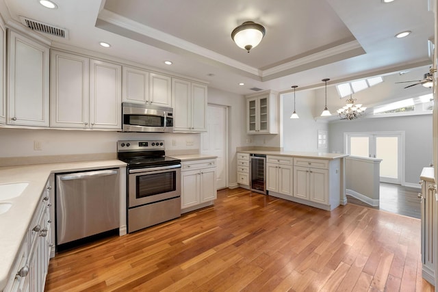 kitchen featuring wine cooler, stainless steel appliances, a tray ceiling, and pendant lighting