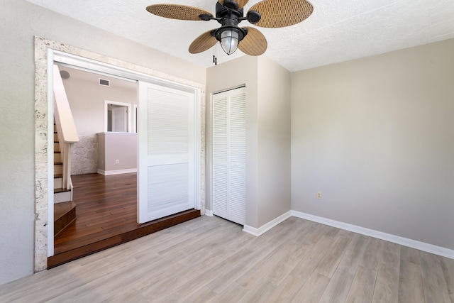 unfurnished bedroom with ceiling fan, a textured ceiling, a closet, and light wood-type flooring