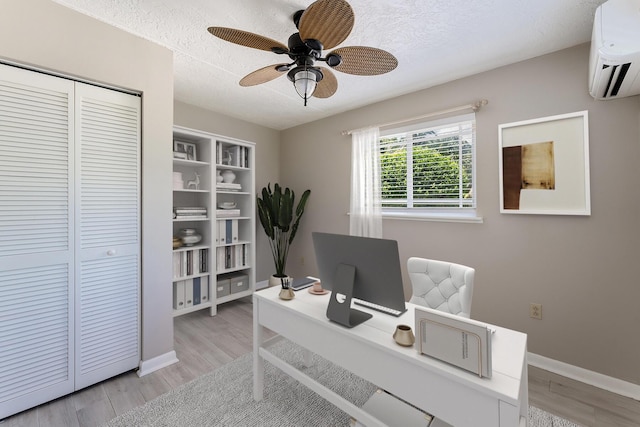 home office featuring ceiling fan, a wall mounted AC, a textured ceiling, and light wood-type flooring