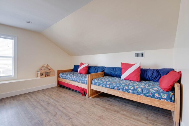 bedroom with wood-type flooring and vaulted ceiling