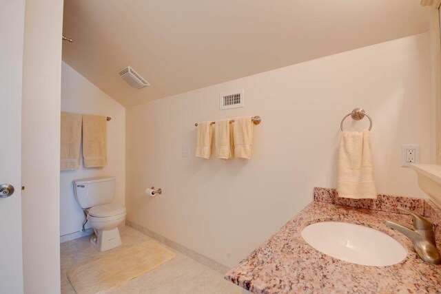 bathroom with lofted ceiling, toilet, tile patterned flooring, and sink