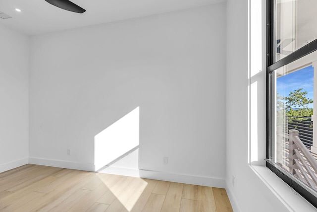 empty room with ceiling fan, visible vents, baseboards, and wood finished floors