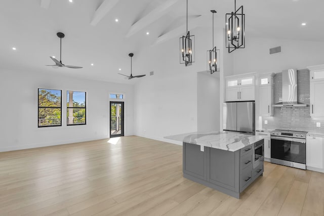 kitchen featuring gray cabinets, visible vents, appliances with stainless steel finishes, open floor plan, and wall chimney exhaust hood