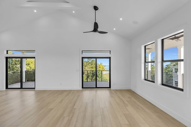 spare room with high vaulted ceiling, a healthy amount of sunlight, and light wood finished floors