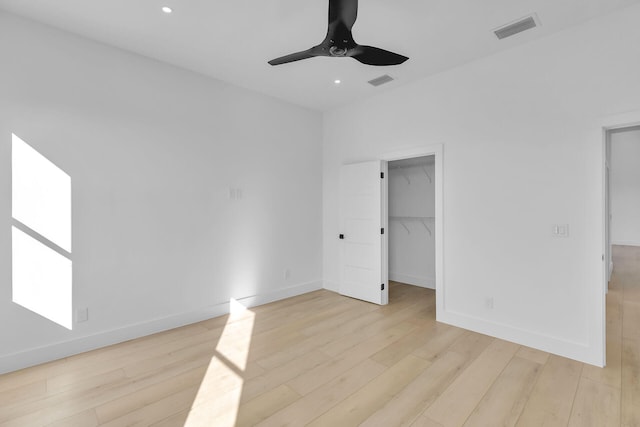 unfurnished bedroom featuring baseboards, a spacious closet, visible vents, and light wood-style floors