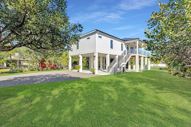 back of house featuring a lawn, ceiling fan, a carport, driveway, and stairs