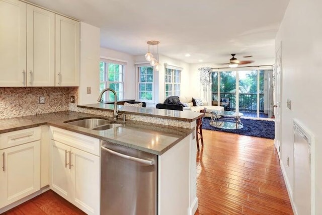 kitchen with sink, stainless steel dishwasher, kitchen peninsula, pendant lighting, and backsplash