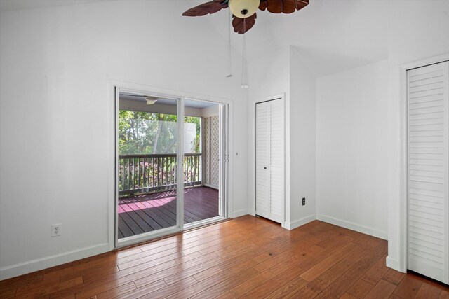 unfurnished bedroom featuring multiple closets, hardwood / wood-style floors, access to exterior, and high vaulted ceiling