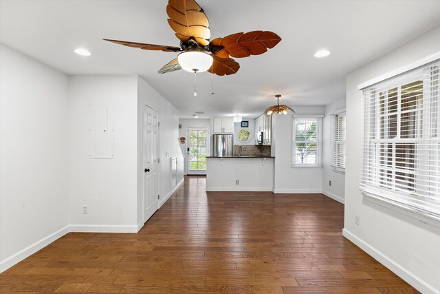 unfurnished living room with a healthy amount of sunlight, dark wood-type flooring, and ceiling fan