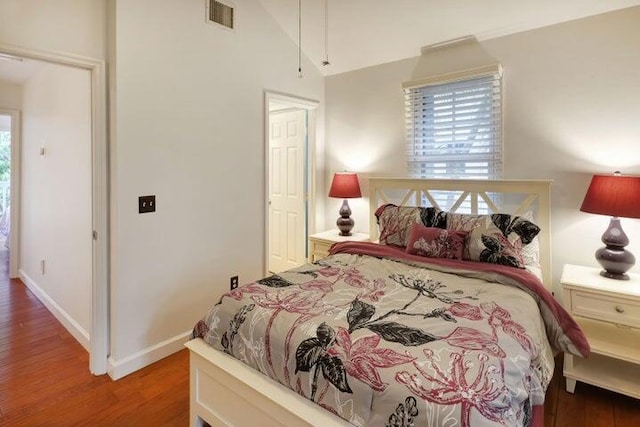 bedroom featuring lofted ceiling, hardwood / wood-style floors, and multiple windows