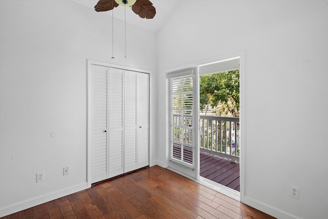 unfurnished bedroom featuring dark wood-type flooring, lofted ceiling, access to outside, a closet, and ceiling fan