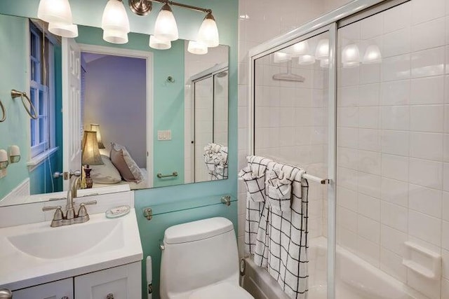 full bathroom with enclosed tub / shower combo, vanity, and toilet