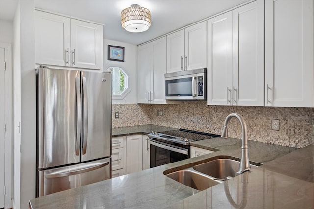 kitchen with tasteful backsplash, appliances with stainless steel finishes, dark stone countertops, and white cabinets