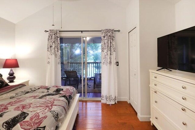 bedroom with lofted ceiling, access to exterior, and dark hardwood / wood-style floors