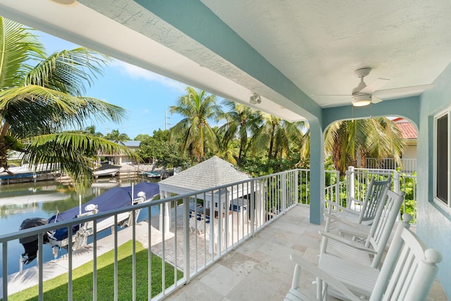 balcony with ceiling fan and a water view