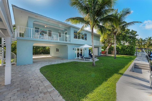 back of property featuring a lawn, a carport, and ceiling fan