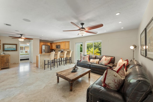 living room featuring ceiling fan and a textured ceiling