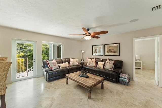 living room with ceiling fan and a textured ceiling