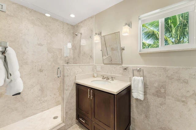 bathroom with vanity, a shower with door, and tile walls