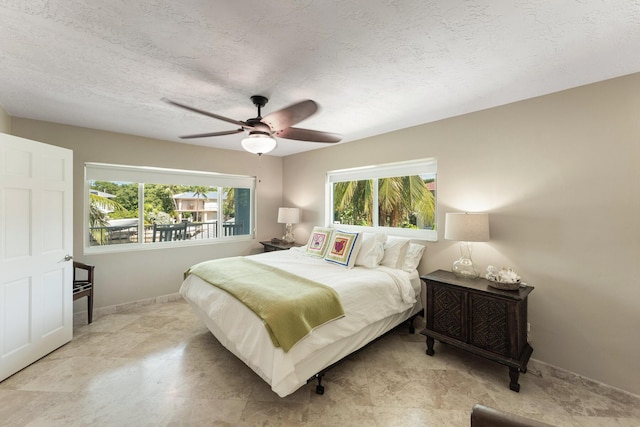 bedroom featuring multiple windows, ceiling fan, and a textured ceiling