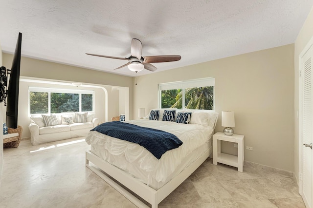 bedroom featuring ceiling fan, multiple windows, and a textured ceiling