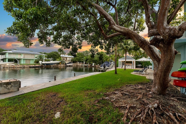 exterior space with a gazebo, a water view, a dock, and a lawn